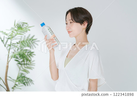 A woman in training wear holding a plastic bottle of water 122341898