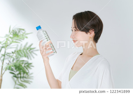 A woman in training wear holding a plastic bottle of water A woman in training wear holding a plastic bottle of water 122341899