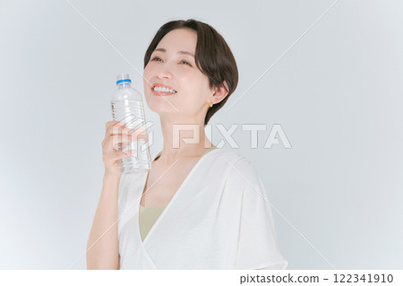 A woman in training wear holding a plastic bottle of water A woman in training wear holding a plastic bottle of water 122341910