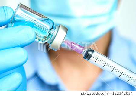 doctor's hand holds a syringe and a blue vaccine bottle at the hospital. Health and medical concepts. 122342034