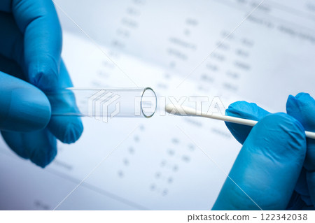 Doctor holds a COVID-19 swab collection, wears blue gloves and a PPE protective mask, and carries a test tube to collect the OP NP and test coronavirus. Doctor holds a COVID-19 swab collection, wears blue gloves and a PPE protective mask, and carries a test tube to collect the OP NP and test coronavirus. 122342038
