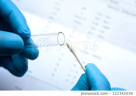 Doctor holds a COVID-19 swab collection, wears blue gloves and a PPE protective mask, and carries a test tube to collect the OP NP and test coronavirus. Doctor holds a COVID-19 swab collection, wears blue gloves and a PPE protective mask, and carries a test tube to collect the OP NP and test coronavirus. 122342039