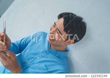 A man laughing at a smartphone A man laughing at a smartphone 122342144