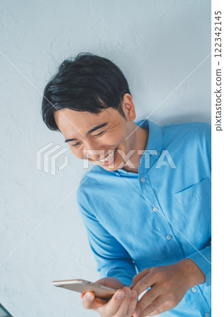 A man laughing at a smartphone A man laughing at a smartphone 122342145