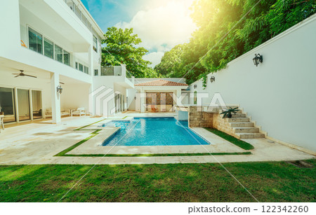 Beautiful crystal clear swimming pool in a backyard. Swimming pool surrounded by nature trees Beautiful crystal clear swimming pool in a backyard. Swimming pool surrounded by nature trees 122342260