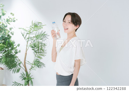 穿著訓練服的女人拿著塑膠瓶水 穿著訓練服的女人拿著塑膠瓶水 122342288
