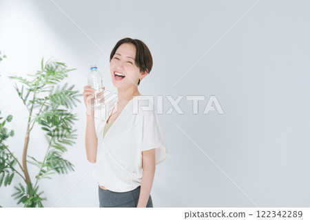 穿著訓練服的女人拿著塑膠瓶水 穿著訓練服的女人拿著塑膠瓶水 122342289