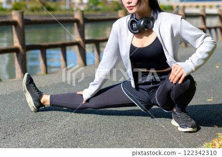 一個酷女人在河邊的人行道上伸展雙腿,散步,節食,散步,鍛煉,修剪。 一個酷女人在河邊的人行道上伸展雙腿,散步,節食,散步,鍛煉,修剪。 122342310