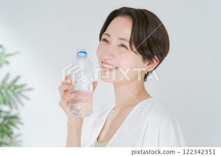 A woman in training wear drinking water from a plastic bottle A woman in training wear drinking water from a plastic bottle 122342351
