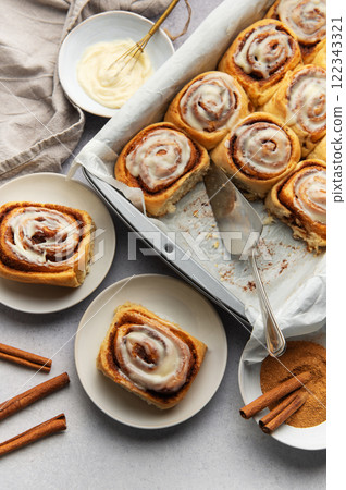 Freshly baked cinnamon rolls with cream cheese frosting and cinnamon sticks 122343321