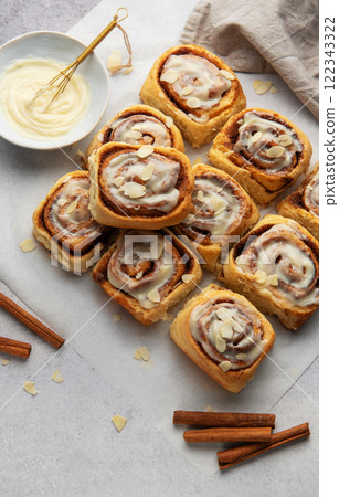 Freshly baked cinnamon rolls topped with icing and almond slivers 122343322