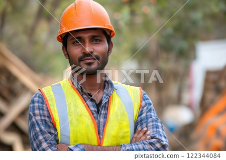 Confident indian construction worker posing with crossed arms at construction site 122344084