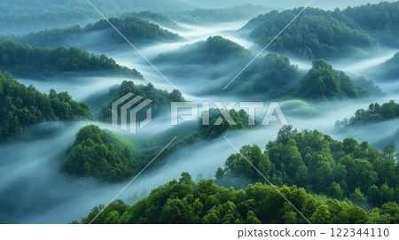 Morning mist flowing over rolling green hills in lush landscape 122344110