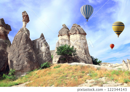 The balloon flight, famous tourist attraction of Cappadocia. Air balloons and Fairy Chimney (multihead stone mushrooms) in Pasabag Valley, Cappadocia, Anatolia, Turkey 122344143