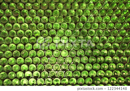 Full frame wall with empty green beer bottles bottoms. Alcohol theme. Endless rows of wine bottles. Green glass bottle wall with sunlight from behind 122344148