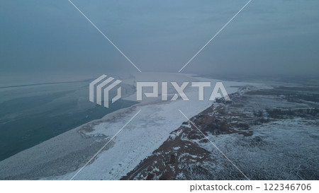 A frozen lake covered with snow in places. A frozen lake covered with snow in places. 122346706