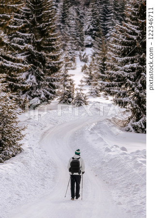 Man Hiking with Trekking Poles in Winter Forest Man Hiking with Trekking Poles in Winter Forest 122346711