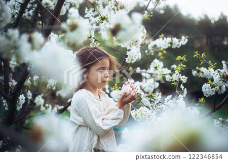 Beautiful young girl holding flowers in her palms, standing in the middle of blooming spring trees. Beautiful young girl holding flowers in her palms, standing in the middle of blooming spring trees. 122346854