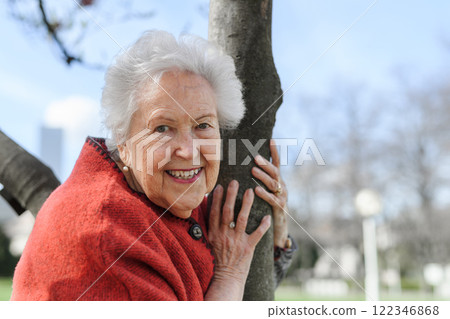 Portrait of lovely elderly woman hugging tree, standing in park. Spring season for senior. Portrait of lovely elderly woman hugging tree, standing in park. Spring season for senior. 122346868