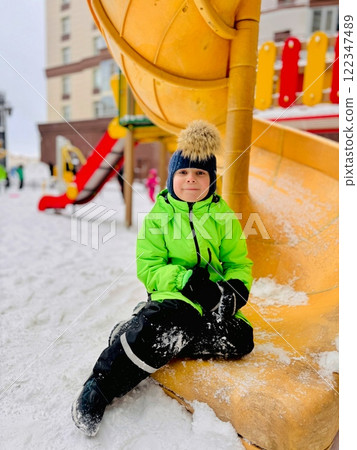 litte boy in neon green overall on playground on winter day litte boy in neon green overall on playground on winter day 122347489