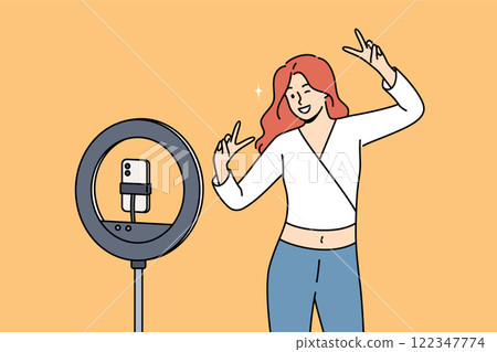 Woman blogger dances in front of phone on tripod with ring lamp, ready-made video for social media 122347774