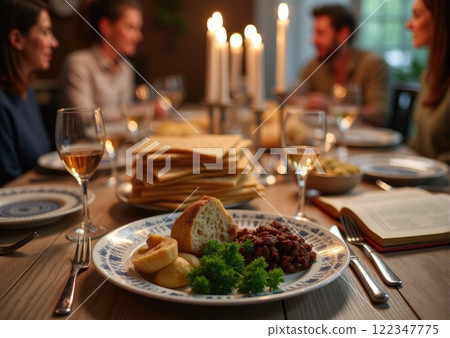 family sitting at the table for Passover Seder with wine, matzo, candles on the table 122347775