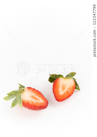 on white photo background there are cut two halves of one ripe strawberry, healthy vitamins, seasonal summer fruit, vitamin C green strawberry tail like a crown 122347799