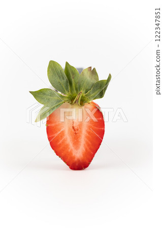 on white photo background there is a cut half of a ripe strawberry suspended in the air healthy vitamins seasonal summer fruit vitamin C green strawberry tail like a crown 122347851