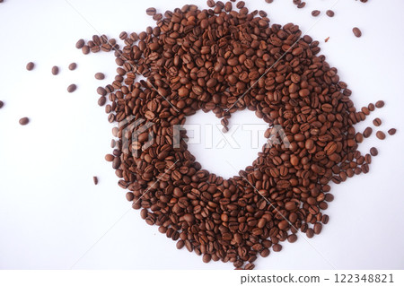 A heart-shaped pile of roasted coffee beans on a clean white background, creatively arranged to symbolize love for coffee and highlighting their rich brown color, texture, and aroma. 122348821