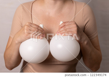A flesh-colored T-shirt woman stands in front of the camera holding balloons in her hands A flesh-colored T-shirt woman stands in front of the camera holding balloons in her hands 122349174