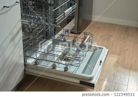 Open empty dishwasher with empty racks and extended basket in modern kitchen ready for loading. Home appliance Open empty dishwasher with empty racks and extended basket in modern kitchen ready for loading. Home appliance 122349531