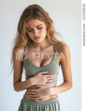 Young woman holding her stomach in pain, feeling abdominal pain or cramps. Period menstruation, women health problem, food poisoning. Created with Generative AI. 122349536