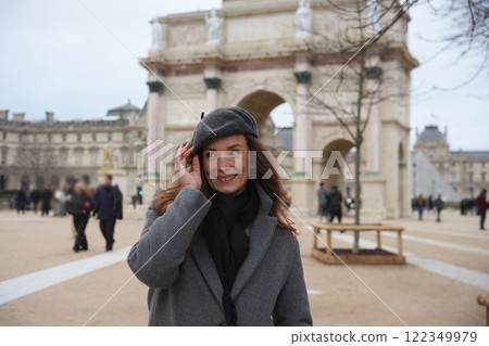 Charming woman adjusting beret near Arc de Triomphe du Carrousel in Paris. Charming woman adjusting beret near Arc de Triomphe du Carrousel in Paris. 122349979