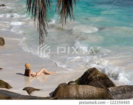 Cute woman sitting on stunning white sand beach 122350485