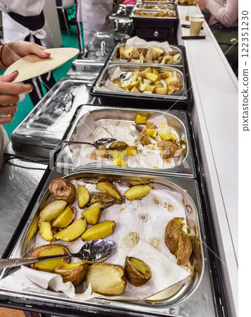 Catering setup with cooked potatoes on display at a dining event in a festive atmosphere Catering setup with cooked potatoes on display at a dining event in a festive atmosphere 122351230