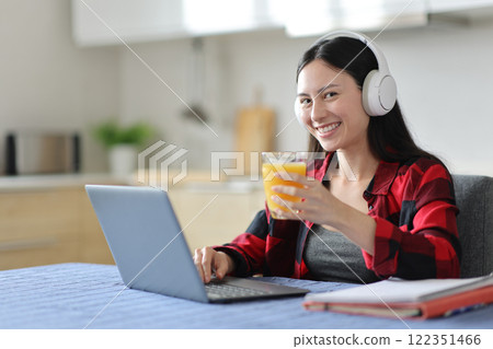 Happy asian student e-learning drinking juice looks at you 122351466