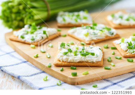 Cheese dip with savory biscuit and and spring onions on a kitchen table, selective focus. 122351993