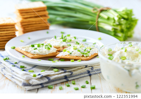 Fresh made snack, cream cheese with spring onions and crackers, on a wooden table, selective focus. 122351994