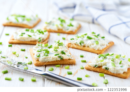 light snack of crackers with cream cheese and green onion on a blue napkin. 122351996