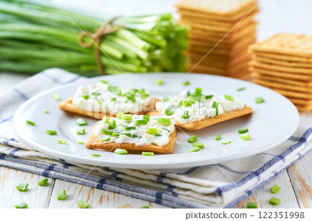 Healthy breakfast concept, biscuits with a cream cheese spread and freshly cut chives on a wooden table. Healthy breakfast concept, biscuits with a cream cheese spread and freshly cut chives on a wooden table. 122351998