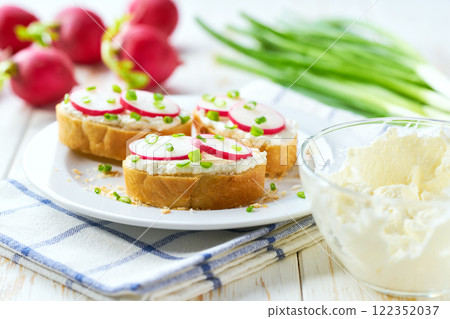 Sliced baguette with soft cheese, radish and freshly chopped chives in a plate. healthy diet snacks. close up. Sliced baguette with soft cheese, radish and freshly chopped chives in a plate. healthy diet snacks. close up. 122352037