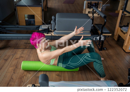 Positive sporty woman doing fascia exercise on the floor - Caucasian female using foam massage roller - tool for back tension and muscle pain release - physical therapy and training stretch concept 122352072