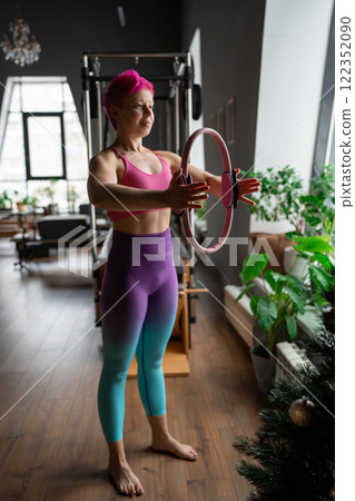 A woman is using a hip Magic Circle at Pilates workout in studio, being active and committed to exercising A woman is using a hip Magic Circle at Pilates workout in studio, being active and committed to exercising 122352090