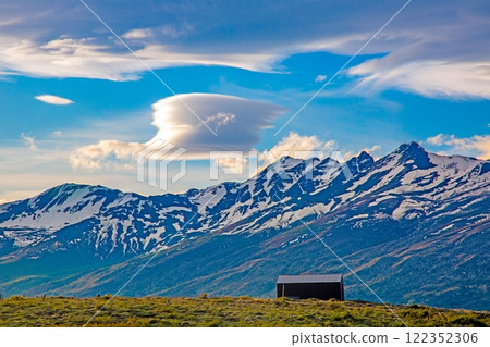 Cabin in front of snow covered mountains and dramatic cloud formations 122352306