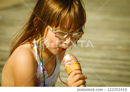 Toddler girl eating ice cream on beach 122352410