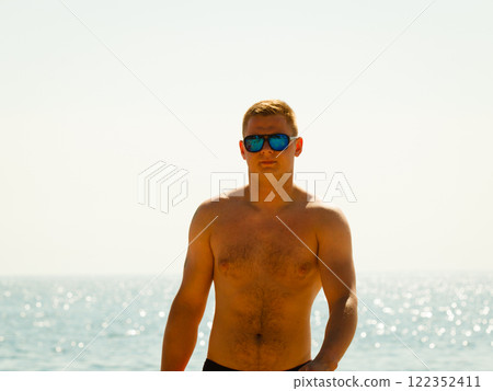 Young sporty man spending vacation on beach 122352411