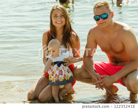 Two adult and baby posing near water Two adult and baby posing near water 122352418