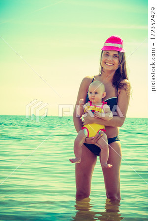 Woman in funny hat hugging baby water Woman in funny hat hugging baby water 122352429