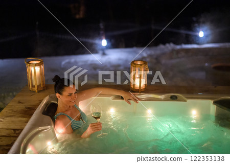 Beautiful woman in hot tub with glass of wine in her hand. Single woman celebrating Valentine's Day alone. Beautiful woman in hot tub with glass of wine in her hand. Single woman celebrating Valentine's Day alone. 122353138