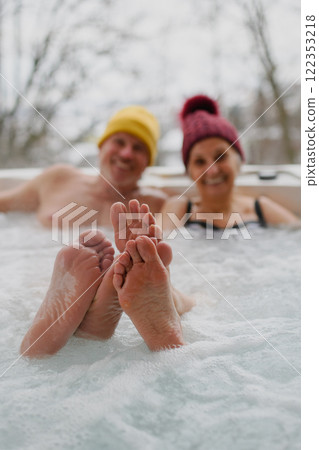 Close up on feet of senior couple bathing in hot tub during cold winter day. 122353218